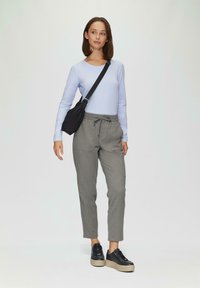 Lichtblauw long sleeve top, grijze taperende broek met trekkoord, zwarte schoudertas en platform sneakers met een gestructureerde zool.
