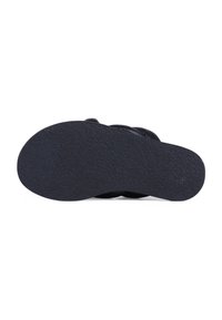 Suela de zapato de goma negra con una superficie texturizada. El diseño incluye un contorno curvado y un patrón de huellas minimalista para proporcionar tracción.