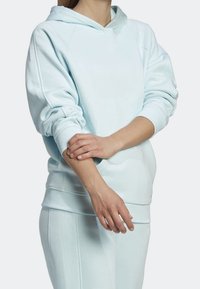 Hoodie bleu clair en tissu doux avec une coupe décontractée, doté d'une grande capuche et de poignets côtelés. Jogging assorti de couleur similaire.