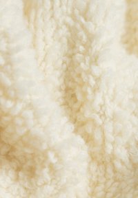 Tissu crémeux, fluffy avec une texture en surface, présentant des boucles denses et un aspect doux et confortable. Matériau polyvalent adapté à diverses utilisations.