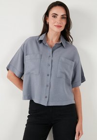 Gray cropped button-up shirt made of light fabric, featuring short sleeves, two chest pockets, and a straight hem.
