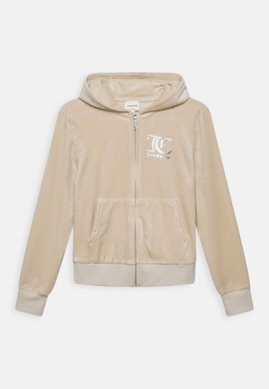 Beiger Juicy Couture Reißverschluss-Hoodie mit Fronttaschen, Bündchen, Kapuze und weißem Logo auf der linken Brust.