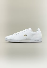 Weiße Ledersneaker mit glatter Textur, ausgestattet mit einem goldenen Logo, runder Zehenpartie und Schnürdesign. Schlichte und minimalistische Gestaltung.
