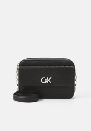 Sac bandoulière rectangulaire noir avec une lanière chaîne argentée et un logo CK argenté sur le panneau avant texturé.