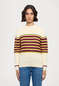 Pull en tricot couleur crème avec des rayures horizontales rouge, vert et bleu, doté de poignets et d'ourlet côtelés.