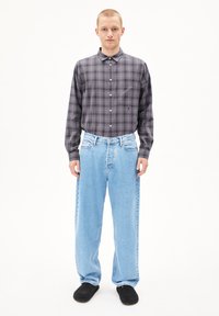 Grijs en zwart geruit overhemd met lange mouwen en een button-down kraag, gecombineerd met lichtblauwe losse jeans en zwarte instapschoenen.