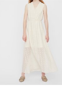 Langes, cremefarbenes ärmelloses Kleid mit V-Ausschnitt, strukturiertem Stoff, elastischem Bund und einem transparenten unteren Abschnitt mit einem geometrischen Muster.
