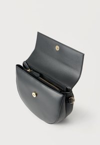 Μαύρη δερμάτινη τσάντα χιαστί ανοιχτή, που δείχνει το μαγνητικό κούμπωμα σε χρυσό τόνο και το εσωτερικό διαμέρισμα με φερμουάρ και χρυσή τσιμπίδα φερμουάρ.