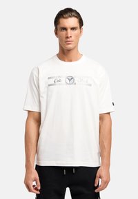 Witte katoenen t-shirt met korte mouwen, voorzien van een zilveren geometrisch grafisch patroon en logo over de borst. Vrije pasvorm.