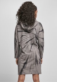 Sukienka z kapturem w szaro-czarny wzór tie-dye, z długimi rękawami, luźnym krojem i spiralnym wzorem na plecach. Wykonana z miękkiego materiału.