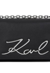 Svart skinnhåndveske med en skinnende krom "Karl" signaturlogo og en sølvkjedehank for bæring. Glatt tekstur med et minimalistisk design.