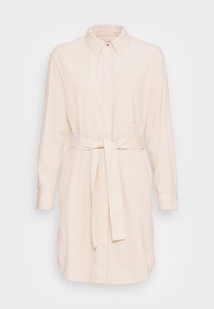 Robe-chemise beige à manches longues avec col, poche poitrine, boutons sur le devant et ceinture assortie en tissu nouée à la taille.