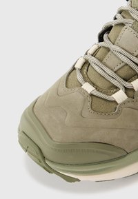 Zielone zamszowe sneakersy z teksturowaną cholewką, jasnymi sznurowadłami i grubą, wyściełaną podeszwą. Posiadają faliste wzory na materiale.