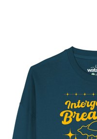 Turquoisekleurig T-shirt met lange mouwen, met gele grafische tekst "Intergalactic Breakfast" met accentsterren en een gestileerd grafisch ontwerp.