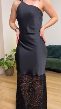 Črna satenska obleka z enim naramnim trakom, z bleščečim čipkastim prekrivanjem ob robu. Gladek tekstura, elegantna zasnova in dolžina do tal.