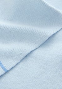 Jasnoniebieska tkanina o fakturze prążkowanej, z gładką, miękką powierzchnią. Złożone warstwy ukazują subtelne różnice odcieni.