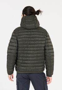 Fodrad jacka i mörkgrön med huva, med en kviltad textur, elastiska ärmslut och en figursydd nederkant. Bakifrån som visar designen och formen.