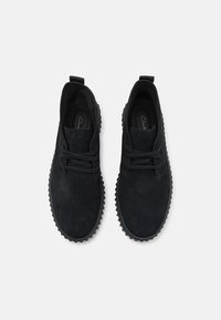 Scarpe nere in suede con punta tonda, lacci piatti e suola in gomma testurizzata. Presentano un design minimal e un'etichetta per una facile calzata.