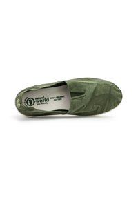 Zelene slip-on čevlje, izdelane iz 100 % ekološkega bombaža, z gladko teksturo in zaobljenim nosom. Notranja etiketa prikazuje podrobnosti o blagovni znamki in materialu.