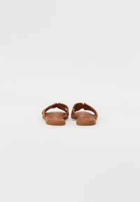 Brune flate sandaler med flettede stropper, åpen tå-design og flat gummisåle. Minimalistisk stil, passende for hverdagsbruk.