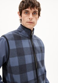 Fleece-Weste in blau und dunkelgrau kariert, mit hohem Kragen und einem durchgehenden Reißverschluss, ausgestattet mit schwarzen Akzenten entlang der Kanten.