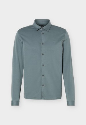Chemise pour homme à manches longues avec boutons, de couleur bleu-gris atténué, dotée d'un col classique et d'un logo brodé discret sur la poitrine.