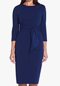 Sinih midi-mekko pehmeästä kankaasta, jossa on pyöreä pääntie ja ¾-hihat sekä edessä solmittava yksityiskohta vyötäröllä.