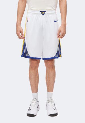 Mand iført hvide basketballshorts med blå og gule sidelister, hvide Nike-sko, hvide sokker og en hvid trøje.