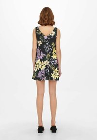 Kwiatowa sukienka na czarnym tle, z żółtymi i fioletowymi kwiatami, z dekoltem w kształcie litery V, luźny krój do połowy uda.