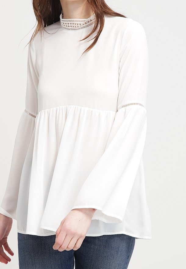 Biała bluzka z długim rękawem z wysokim kołnierzykiem wykończonym koronką, dzwonowymi rękawami oraz luźnym, zwiewnym krojem. Miękki, lekki materiał.