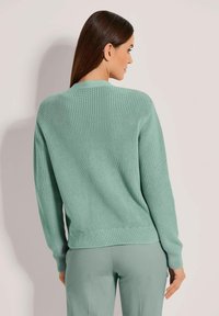 Helles grünes Strickpullover mit strukturiertem Design, gerippten Bündchen und Saum. Glatte Oberfläche, runder Ausschnitt und lockere Passform.