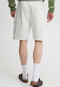 Lysegrå shorts med et subtilt blomsterprint, blød tekstur og elastisk talje. Har en lomme bagpå til opbevaring.