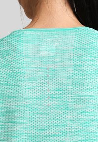 Hellgrünes Strickoberteil mit einem strukturierten Muster und einem runden Ausschnitt. Verfügt über eine Knopfdetails im Nackenbereich. Glatter Stoff.