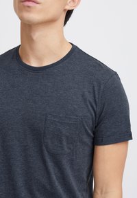Mørkegrå kortærmet t-shirt i et blødt materiale med rund halsudskæring og en lille brystlomme på venstre side.