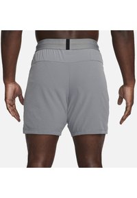 Pantalones cortos deportivos grises con un tejido texturizado, cinturilla elástica con un acento gris claro y un diseño de largo por encima de la rodilla.