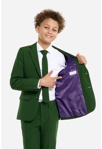 Completo verde con design slim fit, caratterizzato da una camicia bianca e una cravatta. Fodera interna viola con etichetta del marchio visibile. Bottoni sulle maniche.
