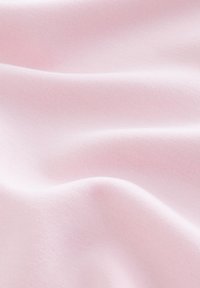 Light pink fabric drapes smoothly, featuring a soft texture with a slight sheen, highlighting subtle folds and waves.