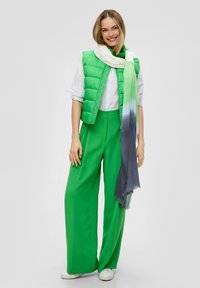 Groene puffer vest, witte shirt, groene wijd-geknipte broek en een gradient blauwe naar groene sjaal. Textuurmaterialen met een gladde afwerking, casual stijl.
