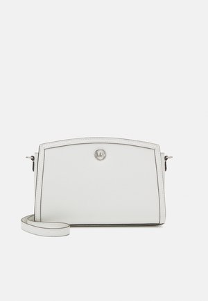 Witte leren crossbodytas met een zilveren rond logo en een verstelbare band op een effen achtergrond.