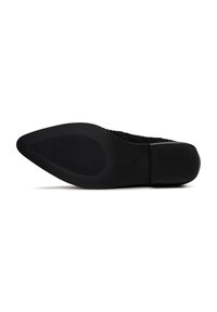 Zapato negro con parte superior de punto, puntera afilada y suela de goma texturizada. La suela presenta ranuras horizontales y una sección de tacón suave.