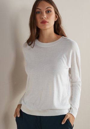 Biały sweter z długim rękawem, wykonany z miękkiego materiału, z okrągłym dekoltem, żebrowanymi mankietami i luźnym krojem. Prosty i uniwersalny design.