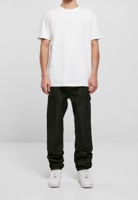 Biała koszulka z krótkim rękawem w połączeniu z ciemnoniebieskimi spodniami cargo. Spodnie mają kieszenie i zwężane nogawki. Noszone z białymi trampkami.