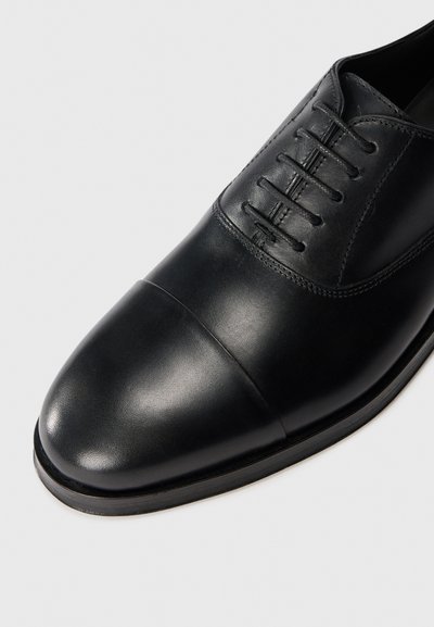 Scarpa da uomo nera in pelle con punta rotonda, design con lacci, finitura liscia e senza adornamenti hardware visibili.