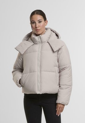 Helle beige Daunenjacke mit hohem Kragen, Reißverschluss und übergroßen Kragen Details. Weiche Textur mit quadratischem Steppmuster.