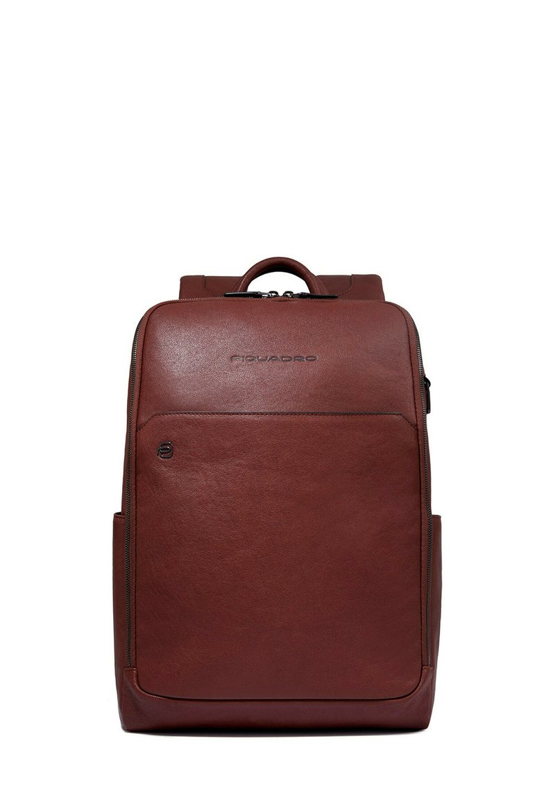 Bruine leren rugzak met een gestructureerd ontwerp, voorzien van een bovenste handvat, een gladde textuur en een voorvak met ritssluiting. Logo gegraveerd aan de voorkant.