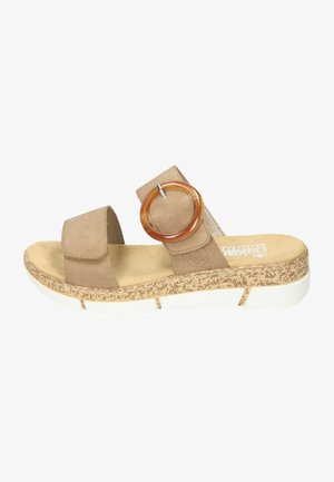 Brown suede slide sandal with a cork-textured sole, white midsole, and a large circular accent in amber color on the strap.