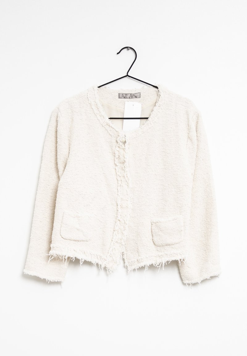 Veste cropped crème en tissu texturé, avec un col rond, des bords effilochés et deux poches avant ; fermée par un seul bouton.