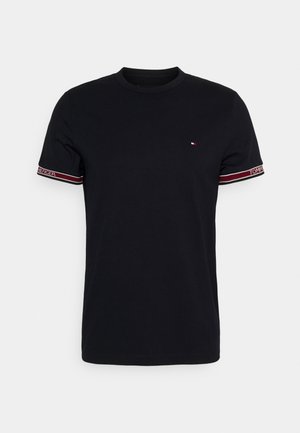 T-shirt noir à manches courtes col rond avec petit logo drapeau Tommy Hilfiger sur la poitrine et bord-côtes rouges et blancs avec branding.