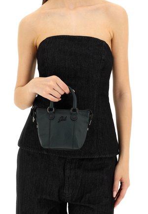 Piccola borsa a tracolla in pelle verde scuro con finitura testurizzata, manici superiori doppi e logo del brand. Indossata da una persona in un top nero senza spalline.