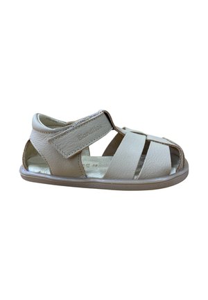 Sandalia de cuero beige con múltiples correas cortadas, cierre de Velcro y suela de goma flexible. Presenta una textura suave y un diseño minimalista.